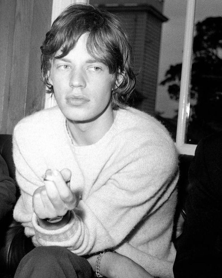 black and white photograph of young man sitting on couch with remote control in his hand