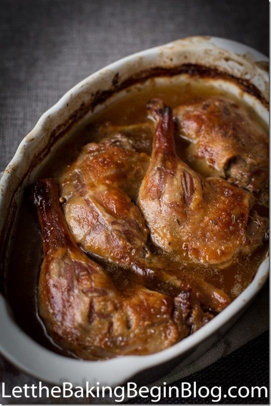 a white dish filled with meat covered in gravy on top of a table