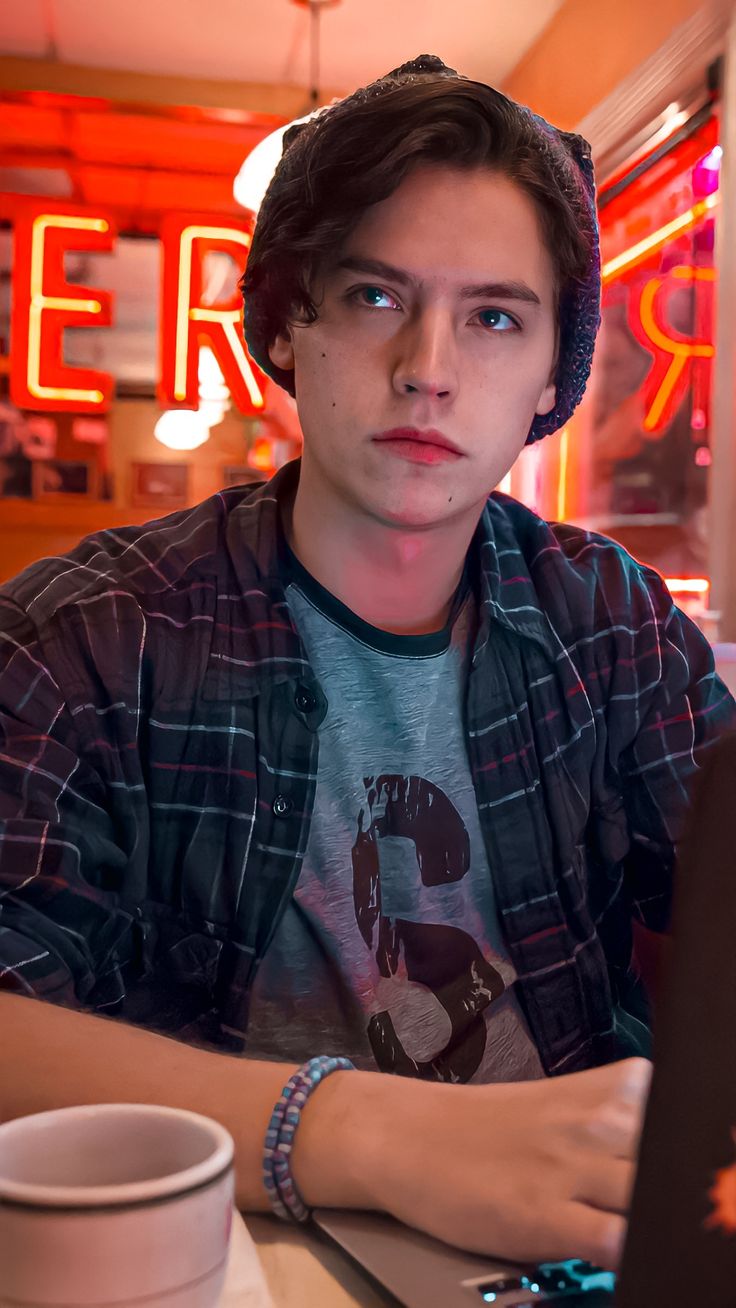 a young man sitting at a table with a laptop computer in front of him,