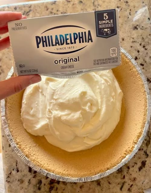 a person holding up a piece of cake with whipped cream on top in a bowl