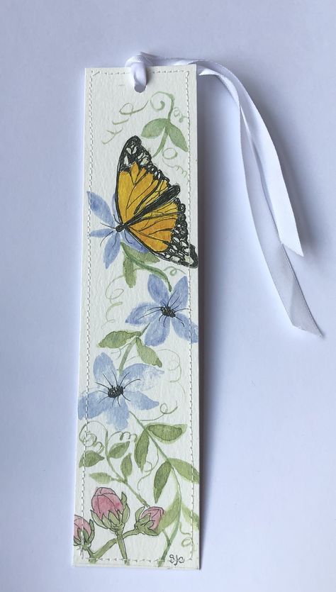 a bookmark with a yellow butterfly and blue flowers on white paper tied to it