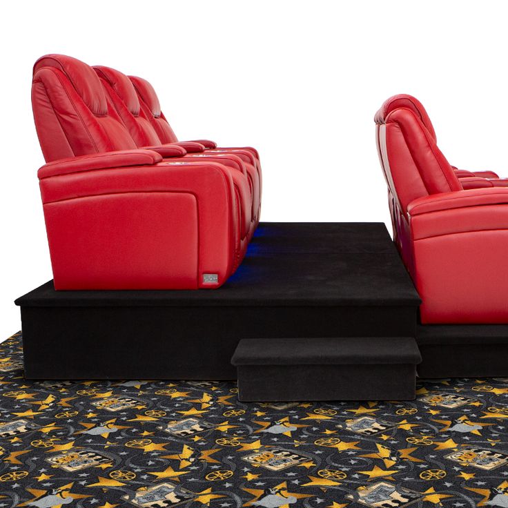 two red reclining chairs sitting on top of a black platform