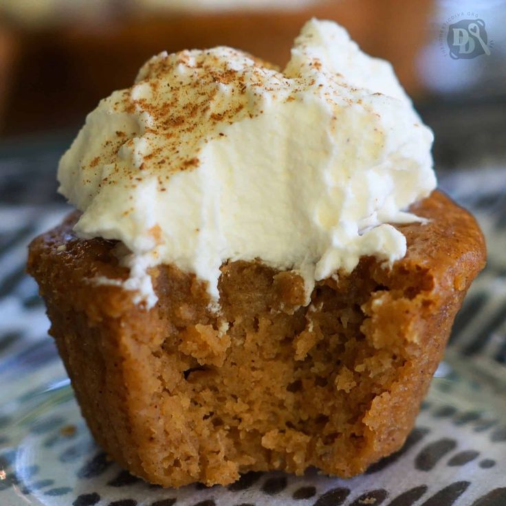 a close up of a muffin on a plate with whipped cream and cinnamon sprinkles