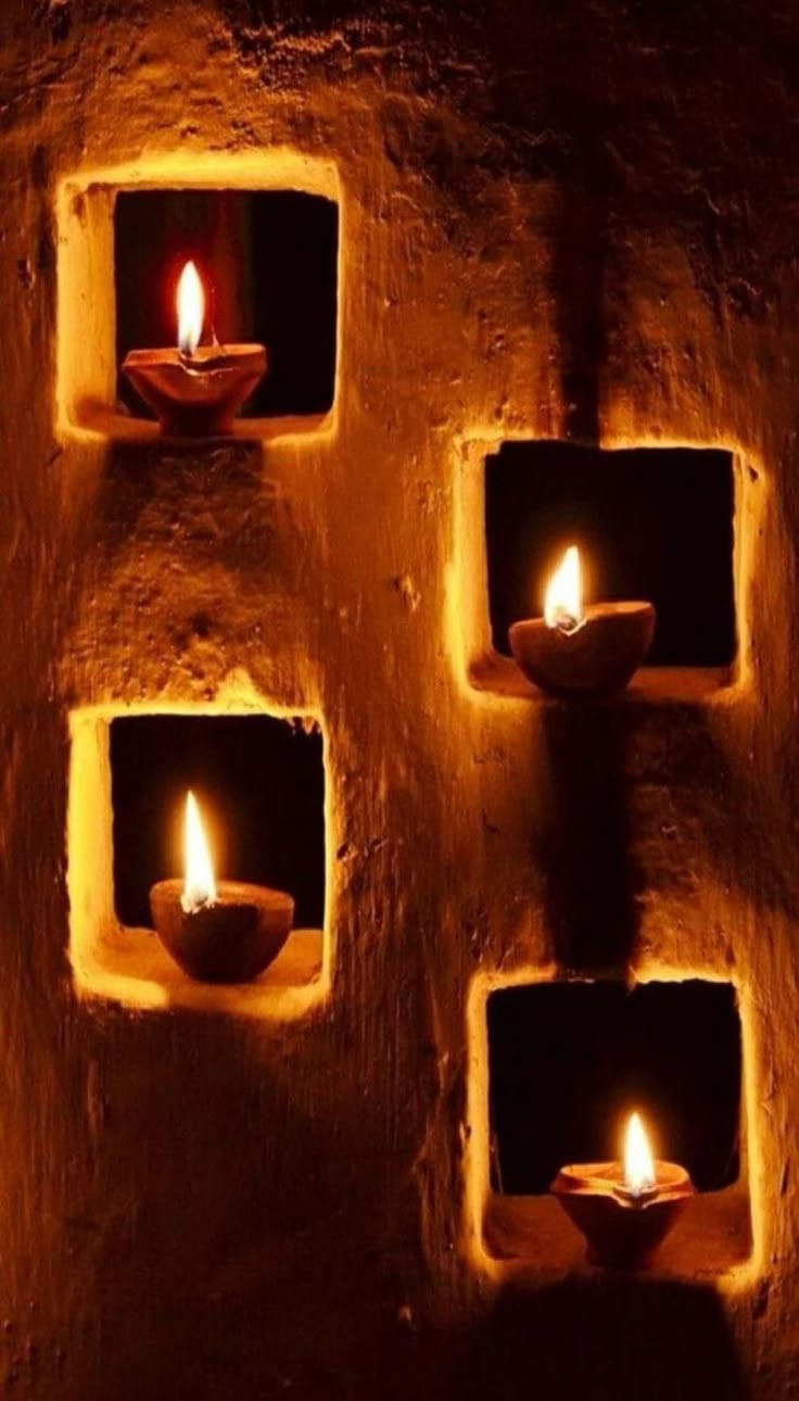 four lit candles are placed in small niches