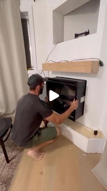 a man kneeling on the floor in front of an open oven and looking at it