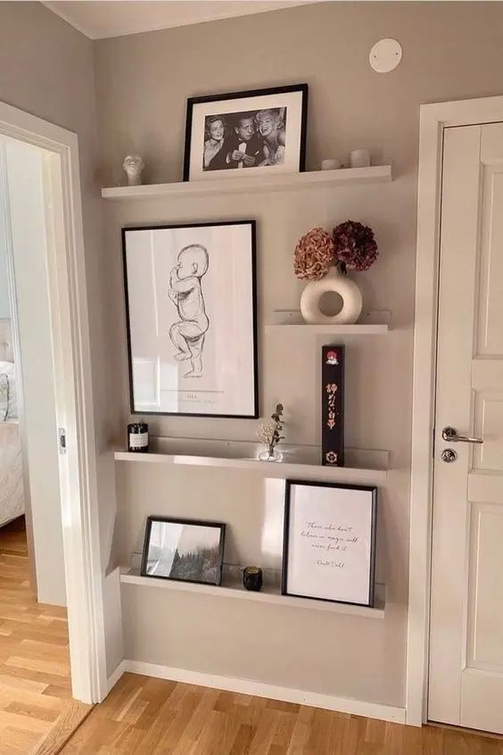 a room with some pictures on the wall and framed photos hanging above it's shelves