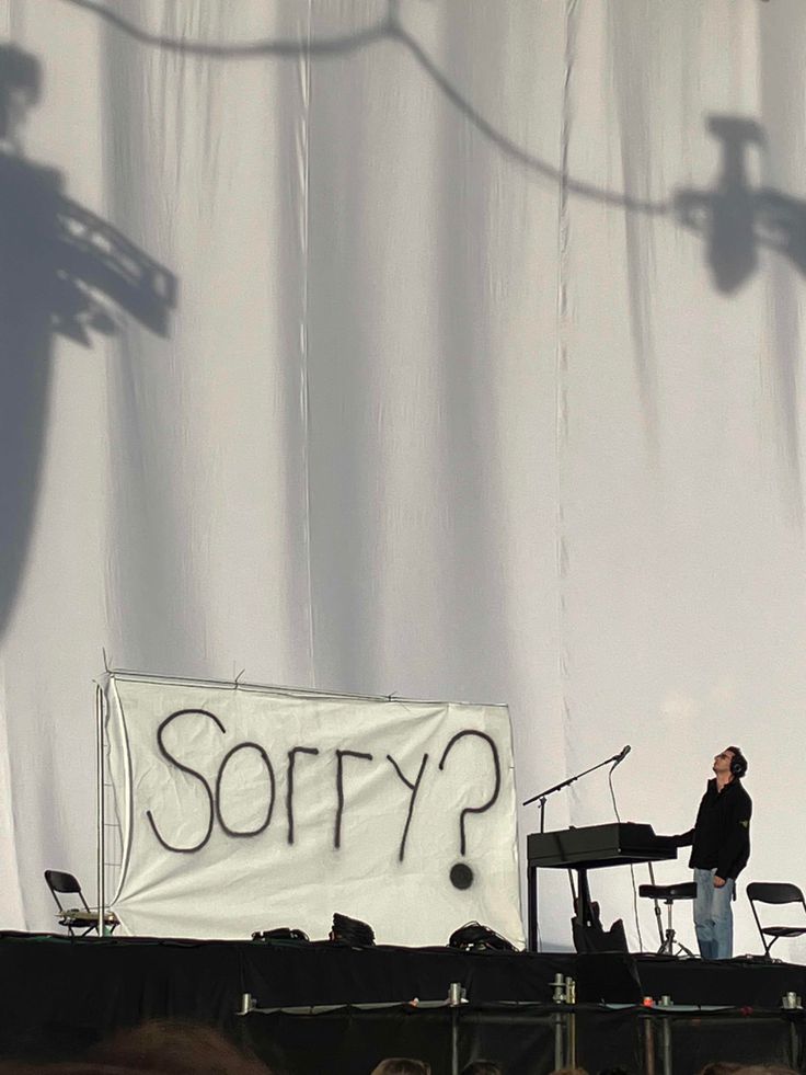 a man standing on top of a stage next to a white sign that says sorry