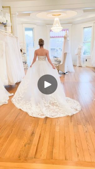 a woman in a wedding dress walking through a room with white dresses on the floor