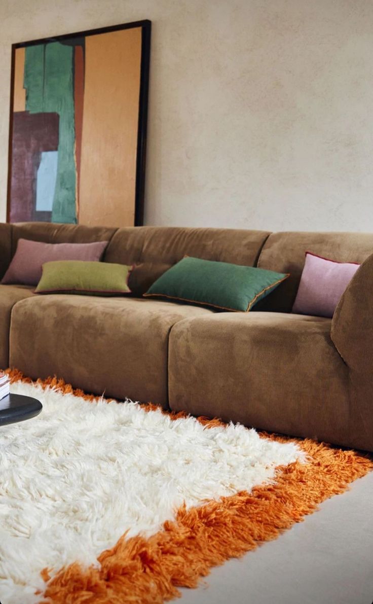 a brown couch sitting on top of a white rug in a living room next to a coffee table