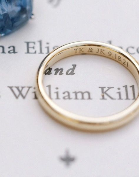 a close up of a wedding ring on top of an open book with a blue stone