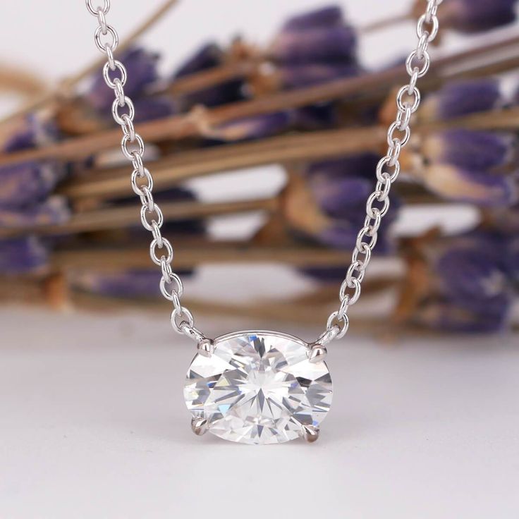 a diamond necklace sitting on top of a table next to purple flowers and dried lavenders