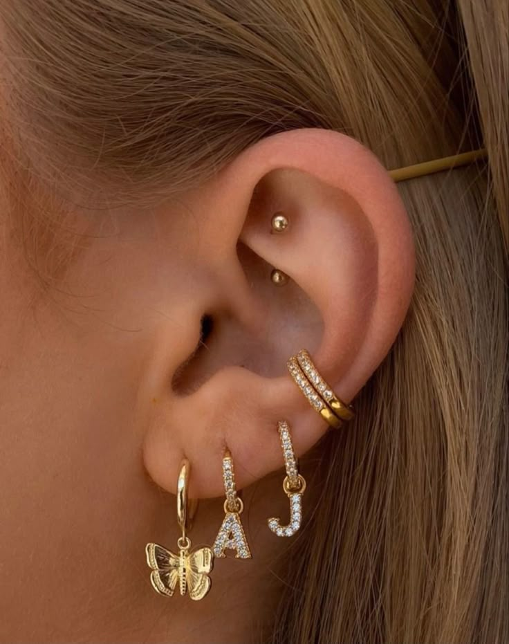 a woman wearing three different ear piercings with the letter j on each one side