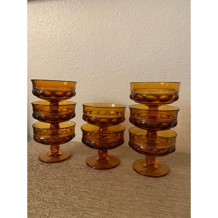 five yellow glass bowls are stacked on top of each other in front of a white wall