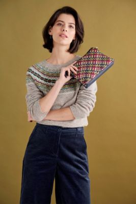 a woman is standing with her arms crossed and holding a purse in front of her face