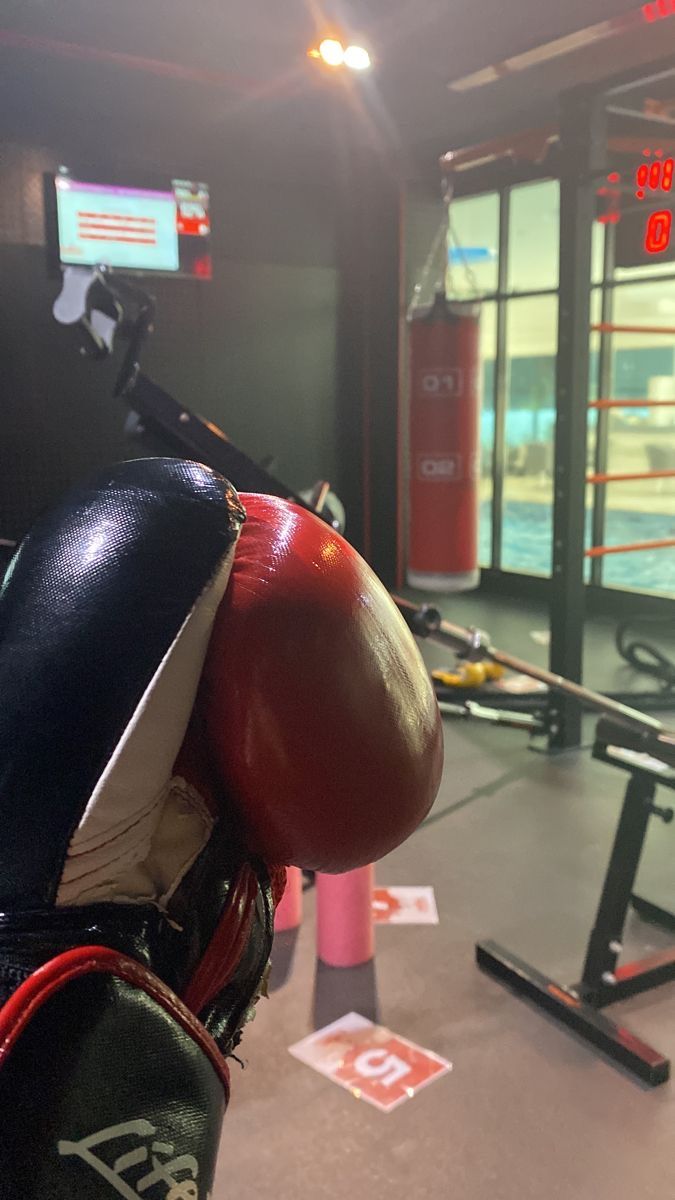 boxing gloves and punching mitts are on display in a gym area with other equipment