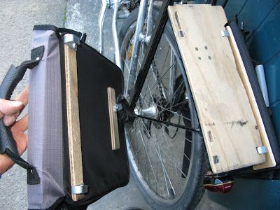 a person holding a piece of luggage next to a bike with it's front wheel