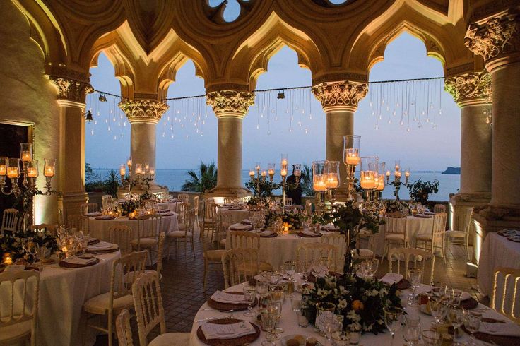 an indoor dining area with chandeliers and tables set up for formal function at dusk