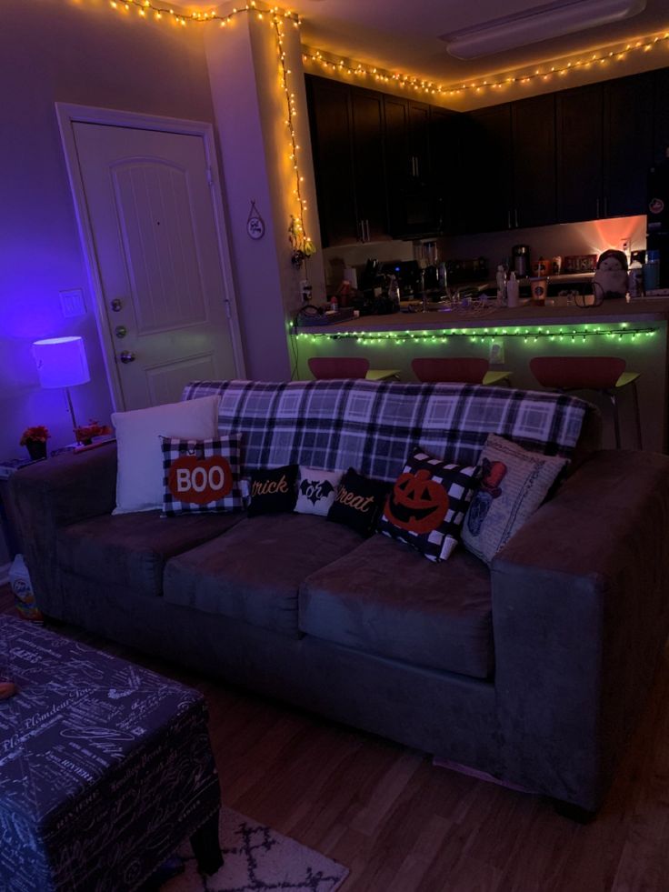 a living room filled with furniture covered in halloween themed pillows and lights on the wall