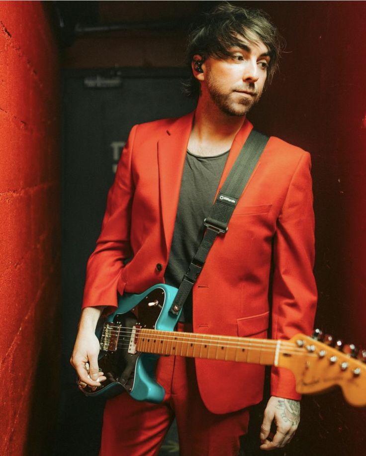 a man in a red suit holding a blue guitar