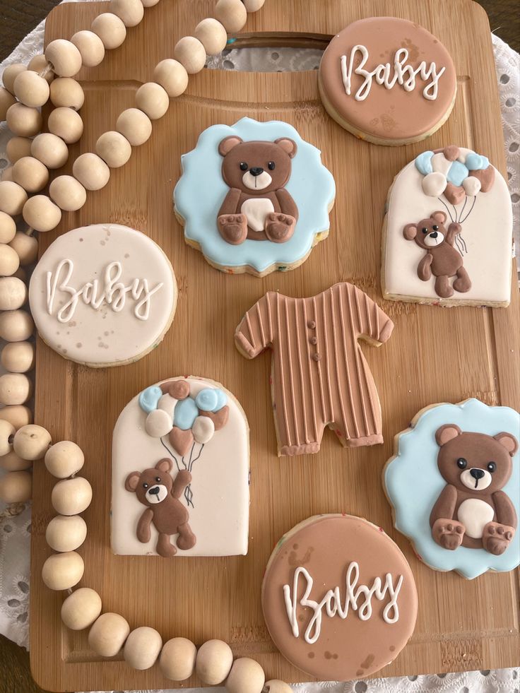 baby shower cookies are arranged on a wooden tray