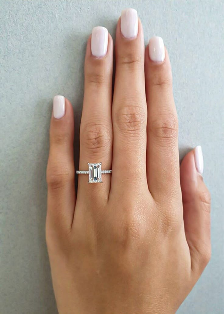 a woman's hand with a diamond ring on her left hand and white nail polish