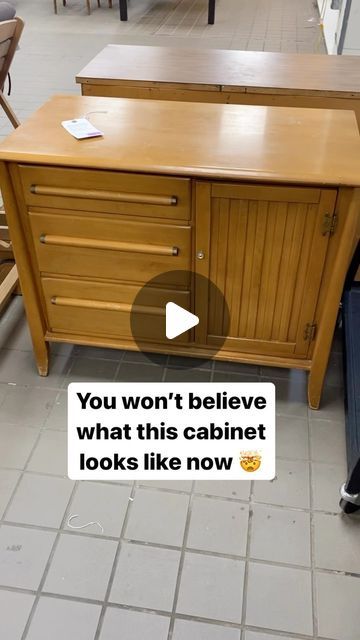 a man standing next to a wooden cabinet on top of a tiled floor in a room