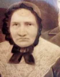 an old photo of a woman with a hat and scarf on, wearing a sweater