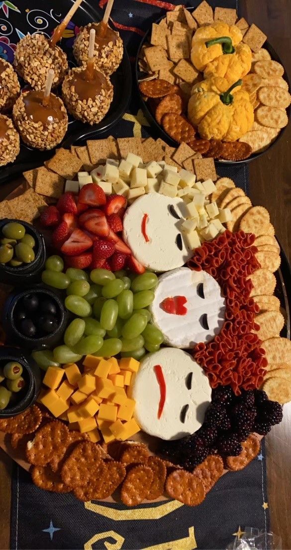 a platter filled with crackers, cheeses and other snacks on top of a table