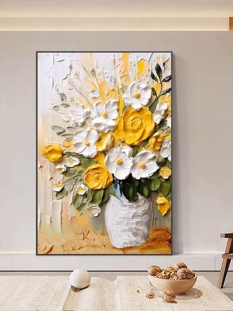 a vase filled with yellow and white flowers sitting on top of a table next to a painting