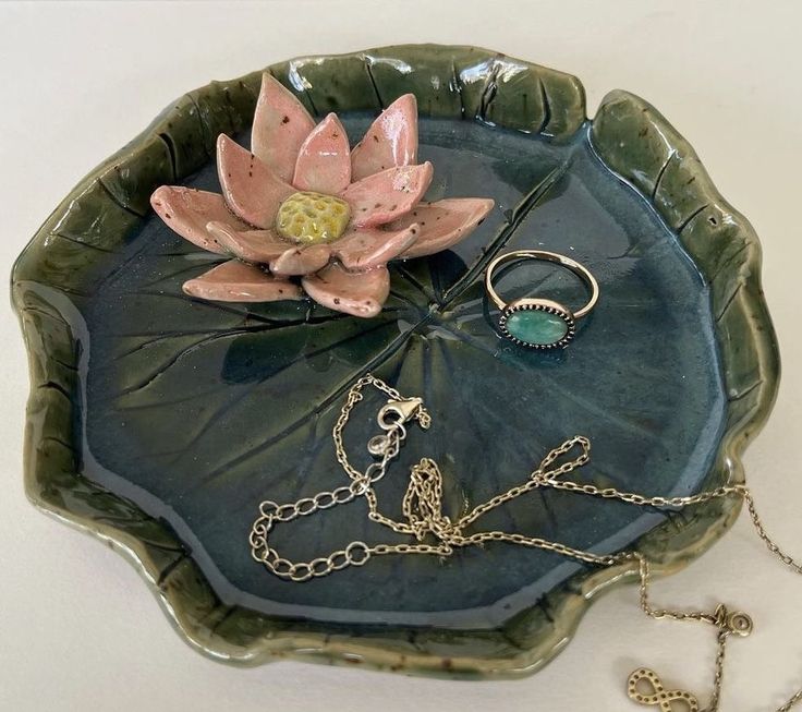 a green plate with a pink flower on it and two gold chains attached to it