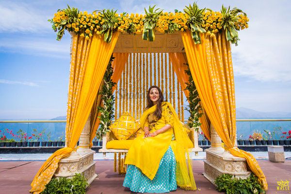 a woman sitting on a bench in front of a gazebo with yellow drapes