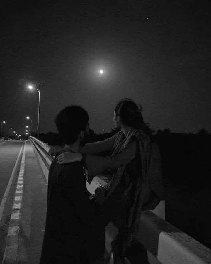 two people sitting on the side of a road at night