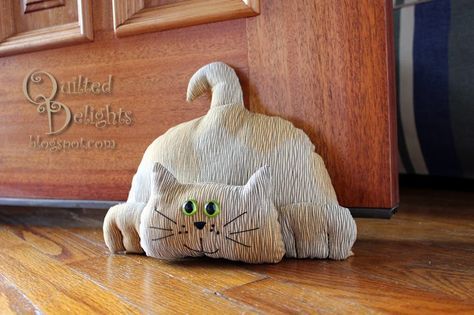 a cat figurine sitting on the floor next to a wooden door