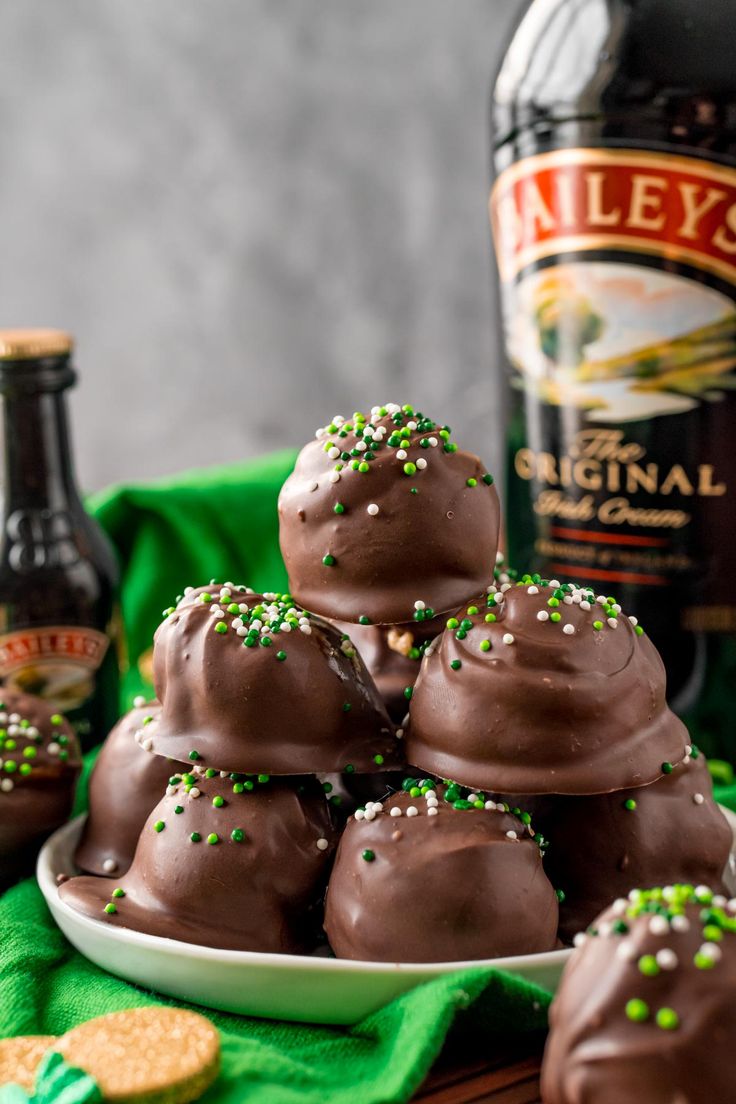 chocolate truffles with sprinkles on a plate next to two bottles