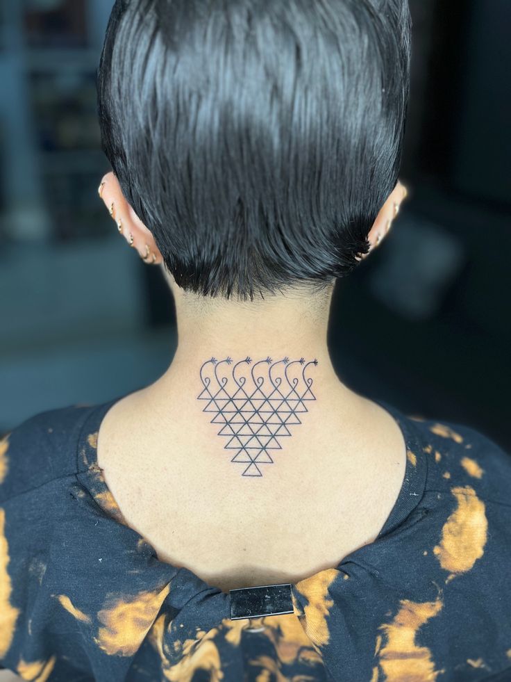 the back of a woman's neck with four symbols on her left shoulder and chest