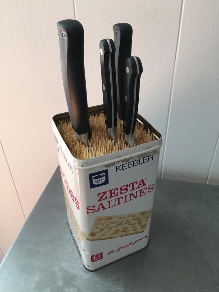 there are several knives in a tin on the table with some sort of salt and pepper