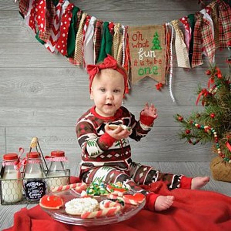 a baby sitting on the floor with food in front of her and christmas decorations around her