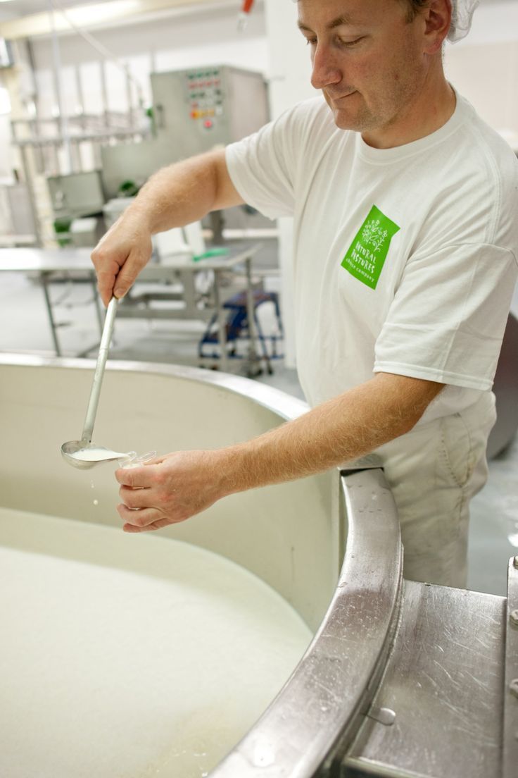 a man in a white shirt is cleaning a metal tub with a brush and spoon