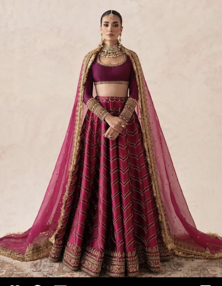 a woman in a maroon and gold lehenga