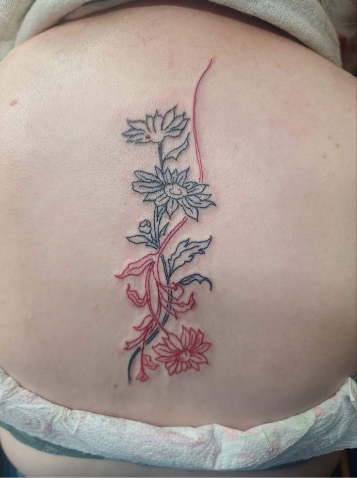 a woman's back tattoo with flowers on it