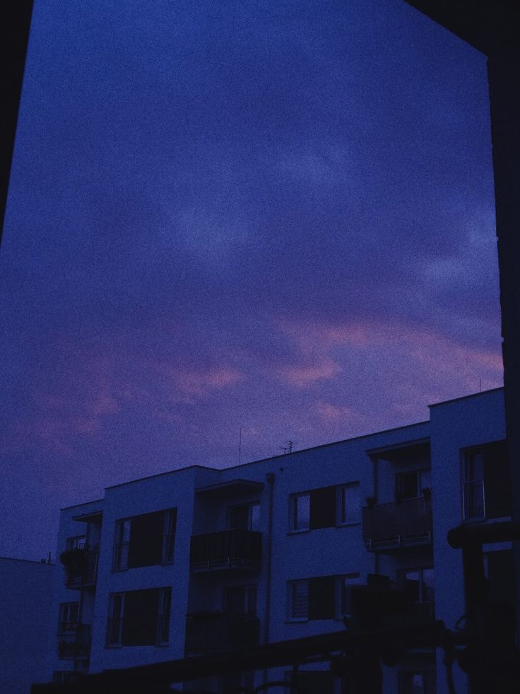 an apartment building is silhouetted against the evening sky with clouds in the foreground