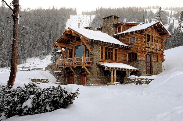 a large log house with snow on the ground