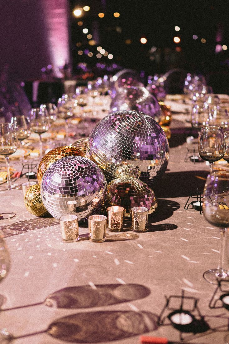 a table topped with lots of shiny disco balls and wine glasses on top of it