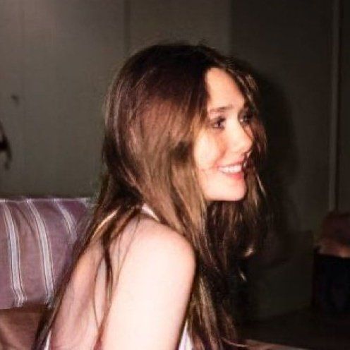 a young woman sitting on top of a couch next to a dog in a living room