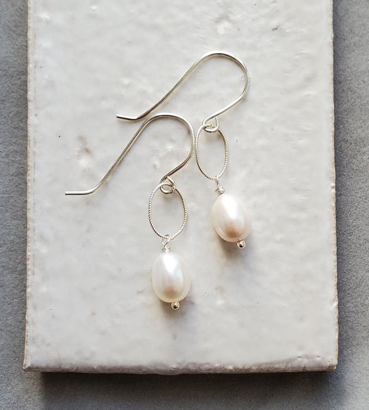 These white oval pearl earrings are a shimmering and chic pair. Delicately handcrafted, these freshwater pearls have been wrapped and end with tiny ball accents. The twisted links add another dainty touch and make them just the right length for many occasions.



These pearl earrings will transition with ease; perfect for causal chic to special evening. Causal Chic, Keshi Pearl Earrings, Pearl Teardrop Earrings, Teardrop Earrings Gold, Grey Pearl Earrings, Silver Wire Earrings, Moonstone Drop Earrings, Silver Chandelier Earrings, Pearl Chain Necklace