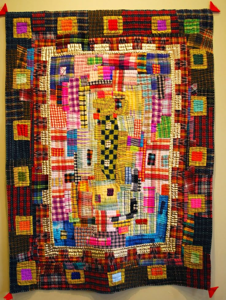 a colorful quilt hanging on the wall with red arrows pointing up at it's center