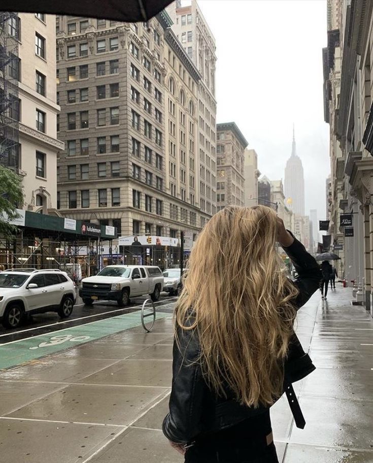 a woman walking down the street in the rain with an umbrella up to her head