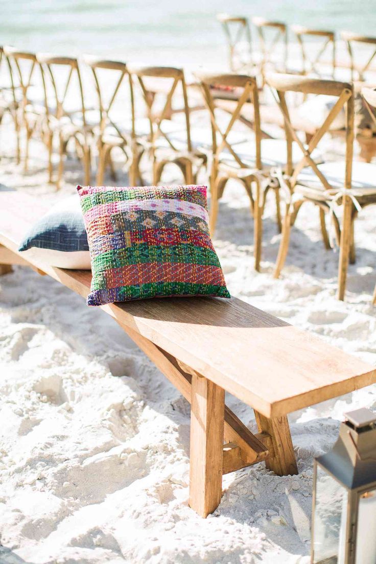 a wooden bench sitting on top of a sandy beach