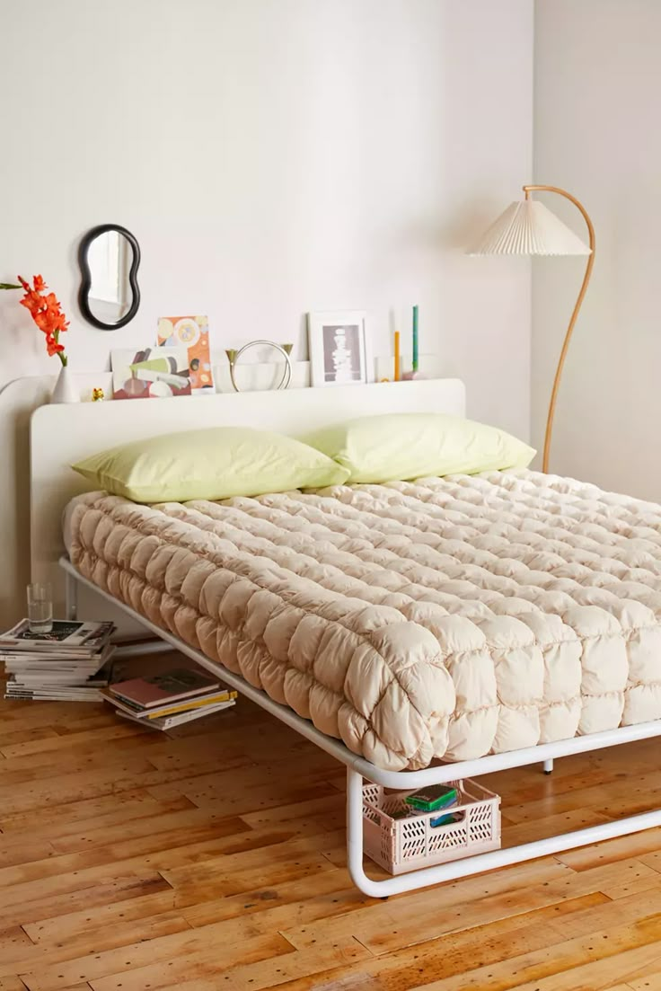 a bed that is sitting on top of a wooden floor in a room with white walls