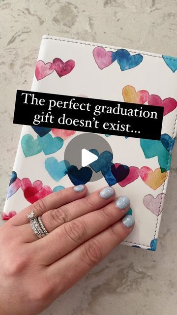 a woman's hand holding a book with hearts on it and the words, the perfect graduation gift doesn't exist